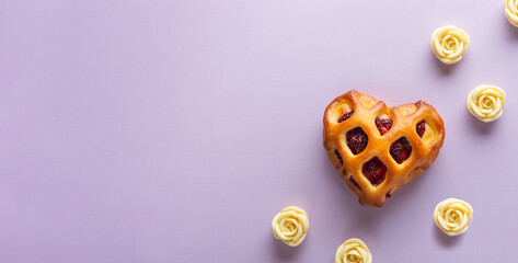 Valentines Day banner. Heart-shaped bun with lattice crust and berry jam on a purple background with white chocolate roses. Flat lay, copy space for text