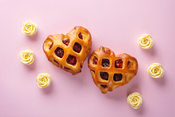 Valentines Day concept. Two heart buns with berry jam and lattice crust on a pink background with white chocolate roses. Top view, close-up, flat lay