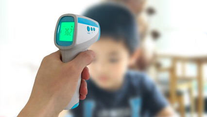 非接触の電子体温計で男の子を検温する手