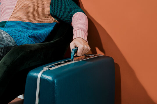 young man grabs the handle of a blue retro suitcase