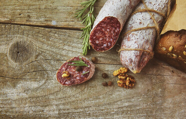 Italian salami wih sea salt, rosemary, garlic and nuts on paper. Rustic style. Close up.
