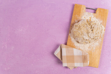 Preparation of the dough with flour on a purple background. Free space for text.