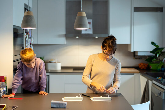 Mother preparing antigen test near curious son
