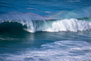 Fototapeta na wymiar Rainbow colors in the spray above a wave