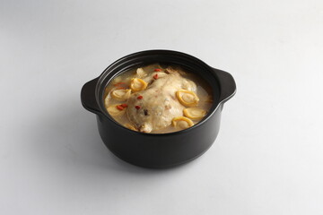 freshly hot stewed whole kampong chicken with abalone seafood in clay pot herbal soup on white background