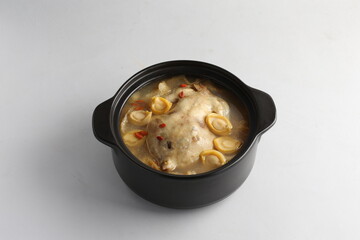 freshly hot stewed whole kampong chicken with abalone seafood in clay pot herbal soup on white background