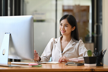 Charming asian woman working with computer at modern office.