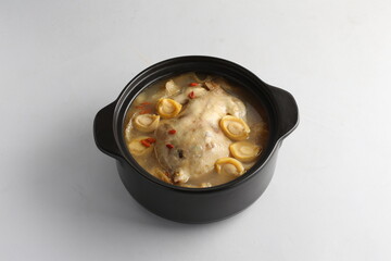 freshly hot stewed whole kampong chicken with abalone seafood in clay pot herbal soup on white background restaurant banquet halal menu