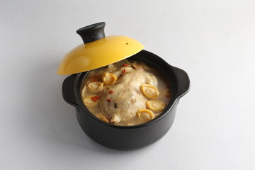 freshly hot stewed whole kampong chicken with abalone seafood in clay pot herbal soup on white background restaurant banquet halal menu