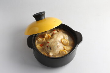 freshly hot stewed whole kampong chicken with abalone seafood in clay pot herbal soup on white background