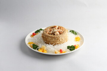 deep fried crispy yam ring with stir fried seafood meat vegetable and cashew nut in sauce and white vermicelli on white background chinese banquet menu