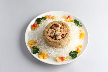 deep fried crispy yam ring with stir fried seafood meat vegetable and cashew nut in sauce and white vermicelli on white background chinese banquet menu