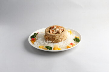 deep fried crispy yam ring with stir fried seafood meat vegetable and cashew nut in sauce and white vermicelli on white background chinese banquet menu