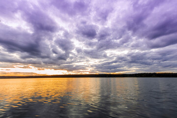 amazing scenic view at a twilight lake from a coast after dramatic colorful sunset with  beautiful clouds and reflection on water surface