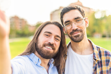 happy gay couple taking a selfie in the park