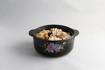 freshly hot stewed Peng cai with  seafood and meat in herbal sauce clay pot and yellow cover on white background Chinese traditional menu