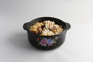 freshly hot stewed Peng cai with  seafood and meat in herbal sauce clay pot and yellow cover on white background Chinese traditional menu