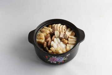 freshly hot stewed Peng cai with  seafood and meat in herbal sauce clay pot and yellow cover on white background Chinese traditional menu