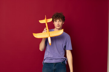 young guy with toy airplane entertainment red background unaltered