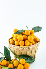 Bamboo basket full of fresh kumquats on white background