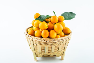 Bamboo basket full of fresh kumquats on white background