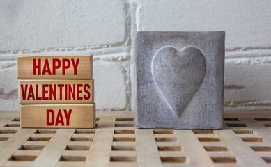 On wooden blocks text, Happy Valentines Day with a candle and a painted heart on a wooden table