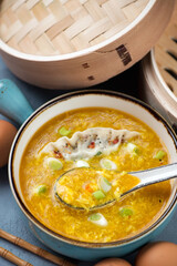 Bowl of chinese traditional egg-drop soup with dumpling and scallions, vertical shot, middle close-up