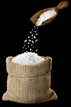 Sea Salt Falling From Wooden Scoop In Burlap Bag