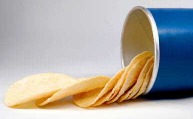 Potato chips are poured out of a can of chips.