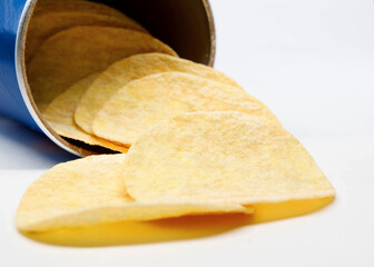 Potato chips are poured out of a can of chips.