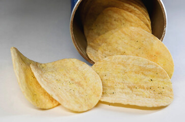 Potato chips are poured out of a can of chips.