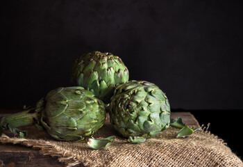 Fresh artichokes hearts on linen table - dark and moody tone