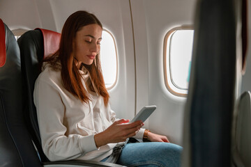 Female passenger using mobile phone in airplane