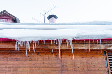 icicles hang on the roof of the house. Dangerous drops of icicles from the roofs of buildings. Removal of icicles from the facade