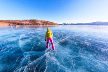 Feet close-ups of skates on legs A brightly colored dressed woman on the blue ice of Lake Baikal
