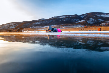 Girl laiing on cracked ice of a frozen lake Baikal