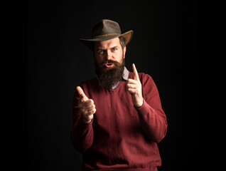 Bearded cowboy man in cowboy hat. Wild west guns, finger revolver shooting. Cowboy man point fingers gun.