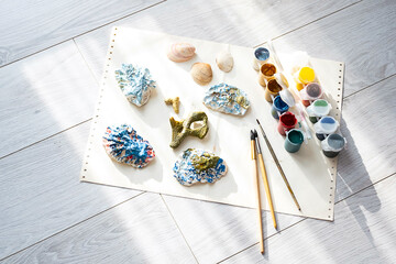 
Child's craft place with shells have been painted different colors, paintbrushes and gouache...