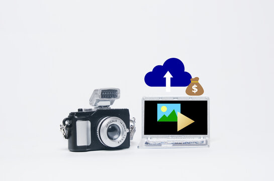 Make money with your camera concept.. Miniature camera with laptop insight, image, video, upload and money bag symbol.