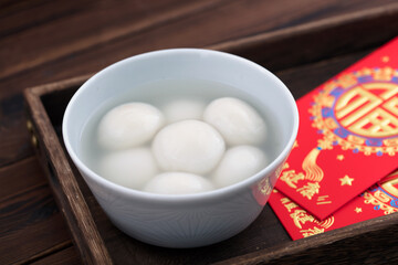 A bowl of dumplings and red envelopes in a food box