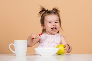 Baby child eating food. Happy smiling baby girl with spoon eats itself.