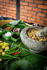 Sambal Pincuk Gooseberry pickle 'Buah Cermai' with ingredients, also known as also known as Otaheite Gooseberry spicy sambal. Selective focus.