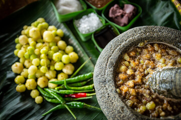 Sambal Pincuk Gooseberry pickle 'Buah Cermai' with ingredients, also known as also known as Otaheite Gooseberry spicy sambal. Selective focus.