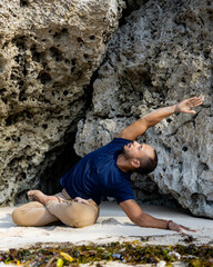 Attractive Asian man sitting in Lotus pose. Padmasana. Side extension. Closed eyes. Side tilt. Yoga retreat. Healthy lifestyle. Self care concept. Flexible spine. Thomas beach, Bali