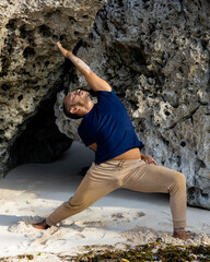 Asian man practicing variation of Virabhadrasana I. Warrior I Pose with twist. Yoga retreat....