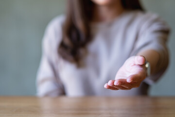 Blurred image of a young woman with reaching hand or giving hand to someone