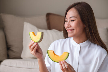 Portrait image of a young woman holding and eating two pieces of Cantaloupe melon