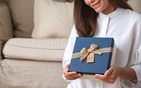 Closeup image of a young woman holding a present box at home