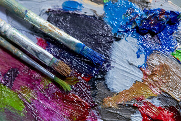 Tubes of oil paint, palette and artist paintbrushes closeup