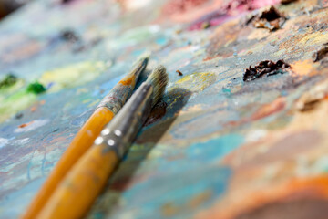Tubes of oil paint, palette and artist paintbrushes closeup